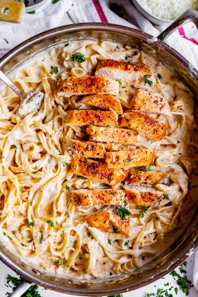 Skillet of creamy chicken Alfredo tossed with fettuccine and parsley.